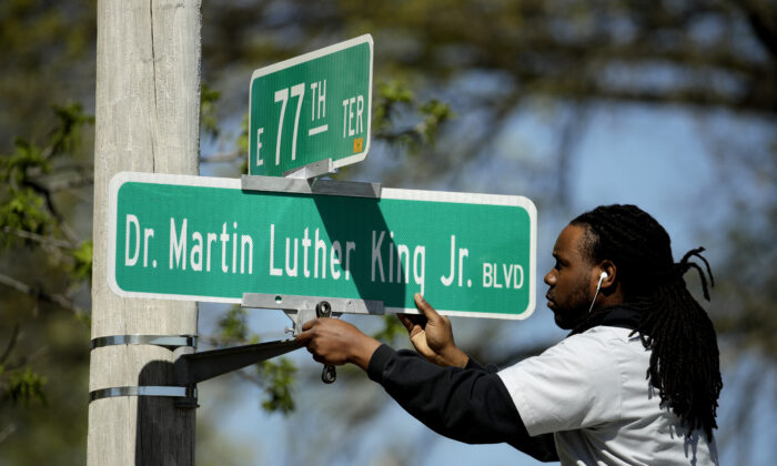 Public works employee Jerry Brooks changes a street sign from The Paseo to Dr. Martin Luther King Jr. Blvd. in Kansas City, Mo. on April 20, 2019. (Charlie Riedel, File/AP Photo)