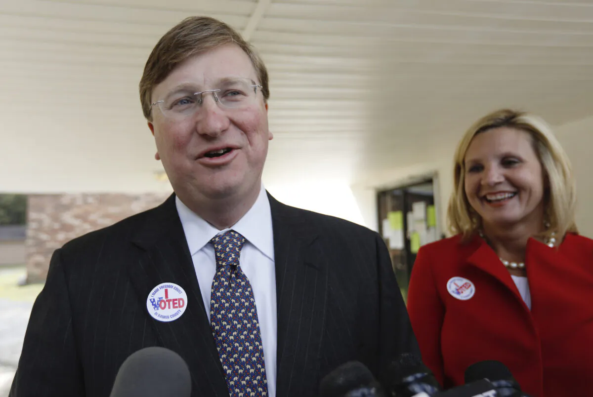 Then-Lt. Gov. Tate Reeves speaks with reporters while his wife, Elee Reeves, laughs at his response outside their Flowood, Miss., voting precinct on Nov. 5, 2019. (Rogelio V. Solis/AP Photo)
