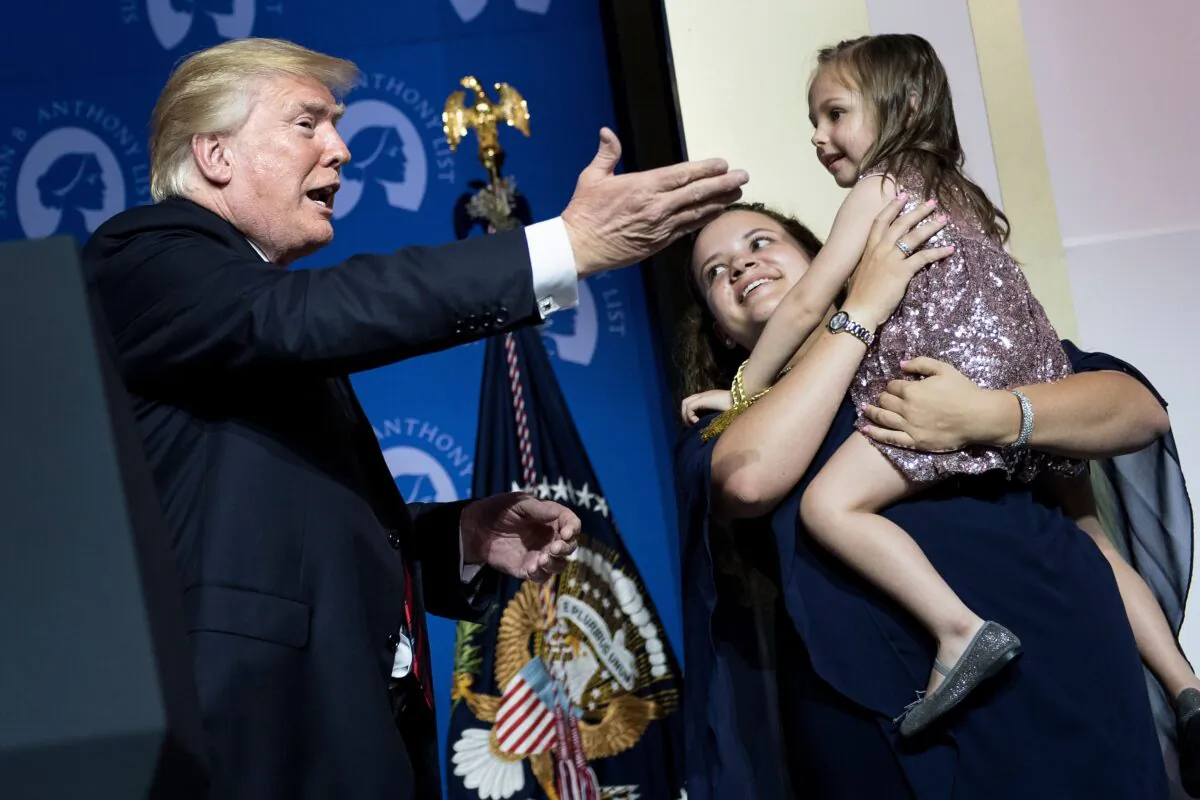 President Donald Trump (L) greets Katharine Alexander, who was born addicted to opioids, and her adoptive mother Lisa Alexander, during the Susan B. Anthony List 11th Annual Campaign for Life Gala at the National Building Museum in Washington on May 22, 2018. (BRENDAN SMIALOWSKI/AFP via Getty Images)