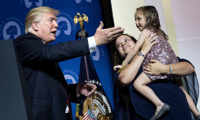 President Donald Trump (L) greets Katharine Alexander, who was born addicted to opioids, and her adoptive mother Lisa Alexander, during the Susan B. Anthony List 11th Annual Campaign for Life Gala at the National Building Museum in Washington on May 22, 2018. (BRENDAN SMIALOWSKI/AFP via Getty Images)