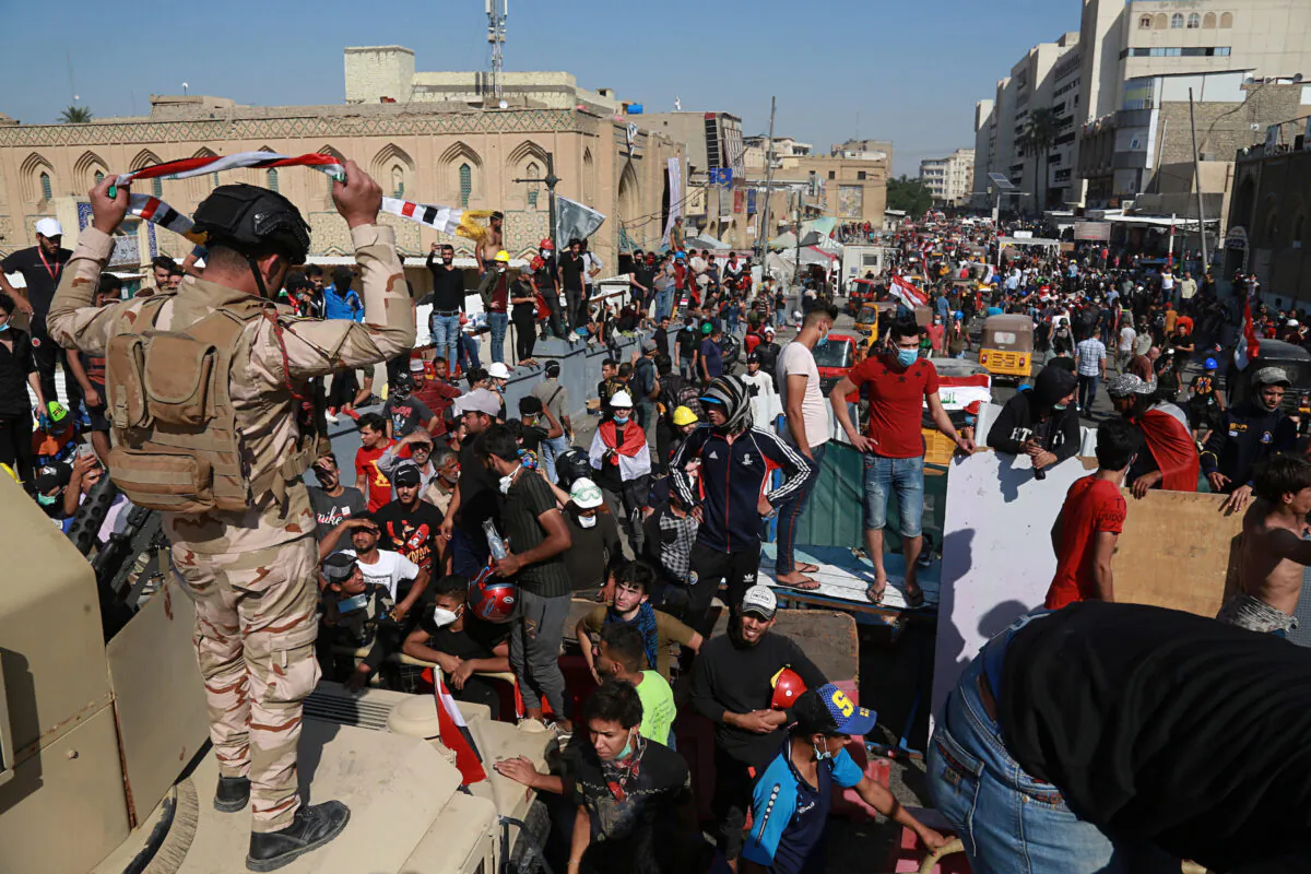 Iraqi Army soldiers trying to prevent protesters from crossing the al- Shuhada (Martyrs) bridge in central Baghdad, Iraq, Nov. 6, 2019. (AP Photo/Khalid Mohammed)