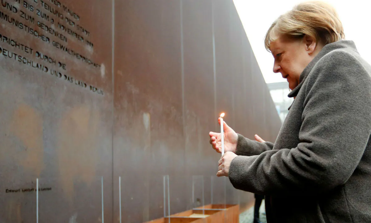 German Chancellor Angela Merkel lights a candle at the memorial of the divided city and the victims of communist tyranny during a ceremony marking the 30th anniversary of the fall of the Berlin Wall at the Wall memorial on Bernauer Strasse in Berlin, Germany on Nov. 9, 2019. (Fabrizio Bensch/Reuters)