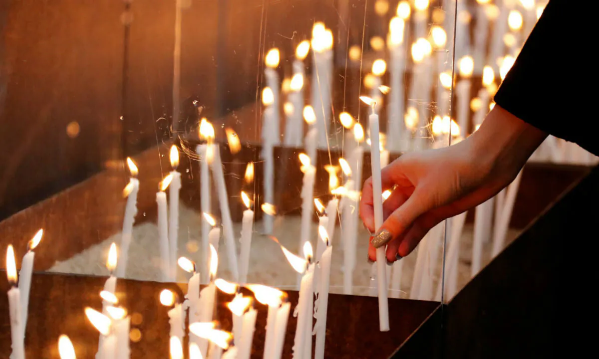 A person lights a candle at the memorial of the divided city and the victims of communist tyranny during a ceremony marking the 30th anniversary of the fall of the Berlin Wall at the Wall memorial on Bernauer Strasse in Berlin, Germany on Nov. 9, 2019. (Fabrizio Bensch/Reuters)