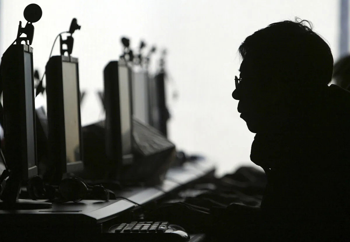 A computer user is silhouetted with a row of computer monitors at an Internet cafe in Shenyang, Liaoning on Jan. 28, 2008. (AP Photo)
