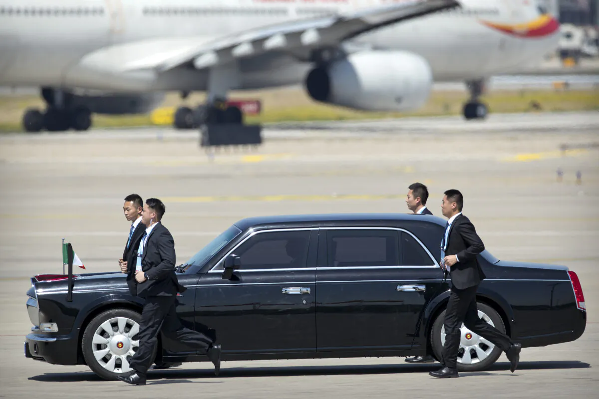 Chinese security personnel jog alongside a car carrying Italian Prime Minister Giuseppe Conte as he arrives at Beijing Capital International Airport to attend the Belt and Road Forum in Beijing on April 26, 2019. (MARK SCHIEFELBEIN/AFP via Getty Images)
