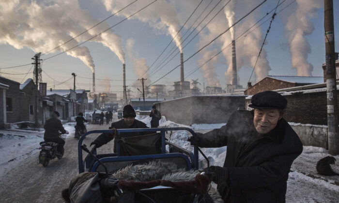 Smoke billows from stacks as Chinese men pull a tricycle in a neighborhood next to a coal fired power plant in Shanxi, China, on Nov. 26, 2015. (Kevin Frayer/Getty Images)