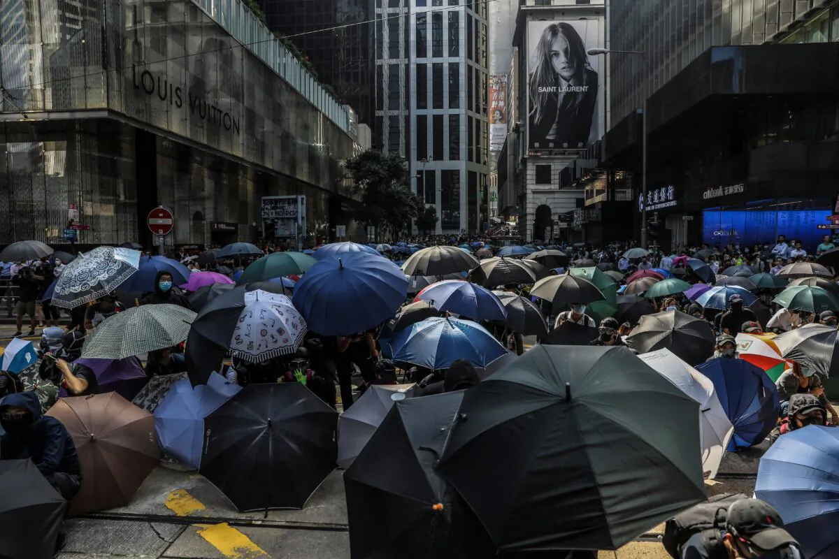 Demonstrators shield beneath umbrellas as police arrive during a flash mob protest in the Central district in Hong Kong on November 13, 2019. (DALE DE LA REY/AFP via Getty Images)