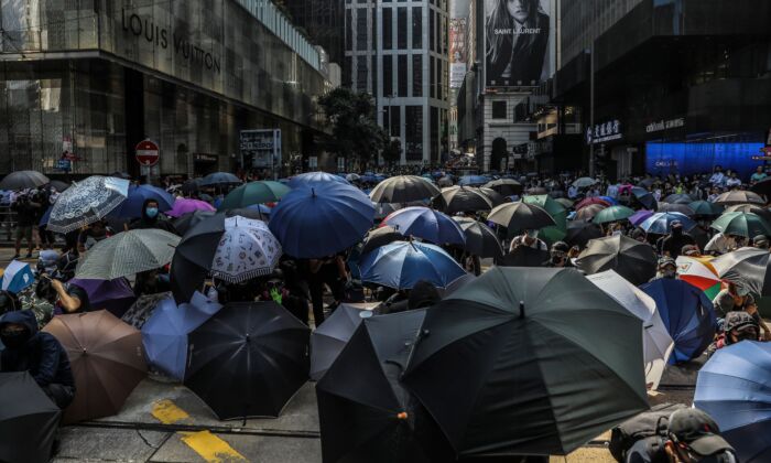 Demonstrators shield beneath umbrellas as police arrive during a flash mob protest in the Central district in Hong Kong on November 13, 2019. (DALE DE LA REY/AFP via Getty Images)