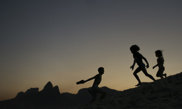 In this Aug. 1, 2016, file photo, children are silhouetted against the setting sun as they run on the sand at Ipanema beach in Rio de Janeiro, Brazil.  (AP Photo/Felipe Dana, File)