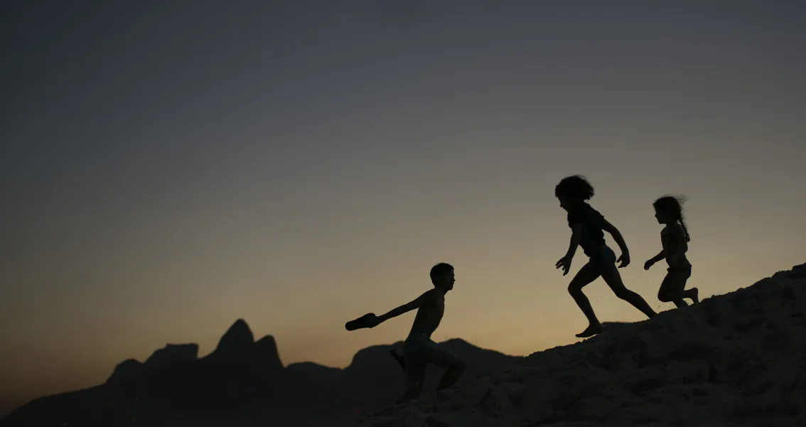 In this Aug. 1, 2016, file photo, children are silhouetted against the setting sun as they run on the sand at Ipanema beach in Rio de Janeiro, Brazil.  (AP Photo/Felipe Dana, File)