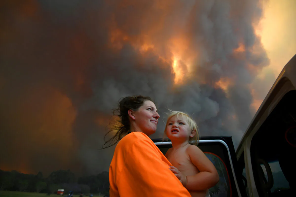 Sharnie Moren and her 18-month-old daughter Charlotte look on as thick smoke rises from bushfires near Nana Glen, near Coffs Harbour, Australia, on Nov. 12, 2019. (Dan Peled/AAP via Reuters)