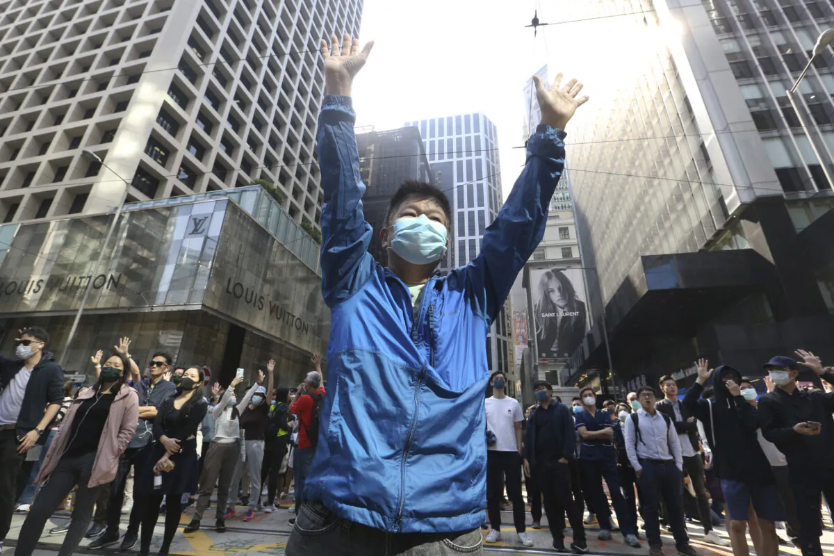 A demonstrator raises his hands during a protest in the financial district in Hong Kong on Nov. 15, 2019. Protesters who have barricaded themselves in a Hong Kong university partially cleared a road they were blocking and demanded that the government commit to holding local elections on Nov. 24. (Achmad Ibrahim/AP)