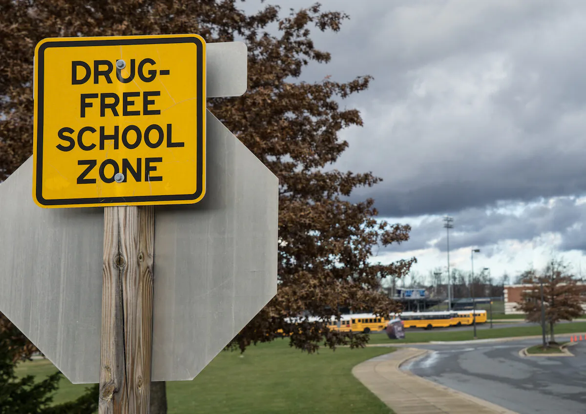 Drug-free school zone sign in front of a high school. (Timur Laykov/Shutterstock)