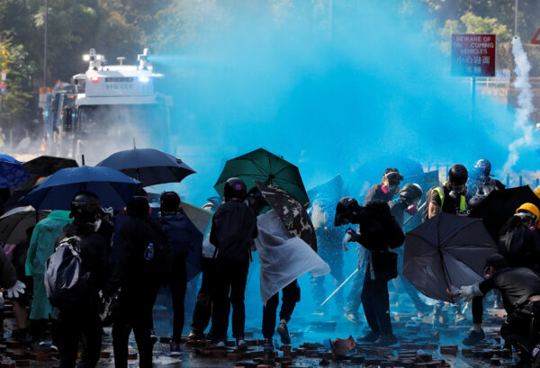 Protesters are sprayed with blue liquid from water cannon during clashes with police outside Hong Kong Polytechnic University