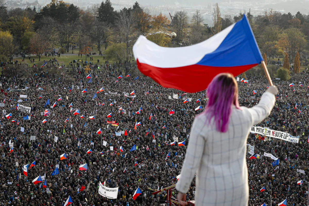 A woman waves a Czech flag from a roof as people take part in a large anti-government protest in Prague, Czech Republic on Nov. 16, 2019. (Petr David Josek/AP)