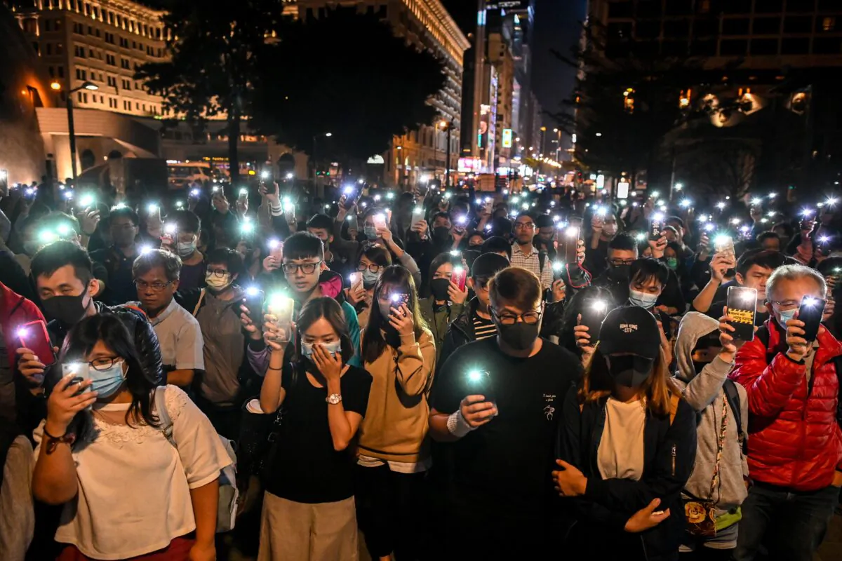 People hold their mobile phones as they gather to pray for the students who are barricaded inside Hong Kong Polytechnic University campus at Salisbury garden in Tsim Sha Tsui district of Hong Kong on Nov. 19, 2019. (YE AUNG THU/AFP via Getty Images)