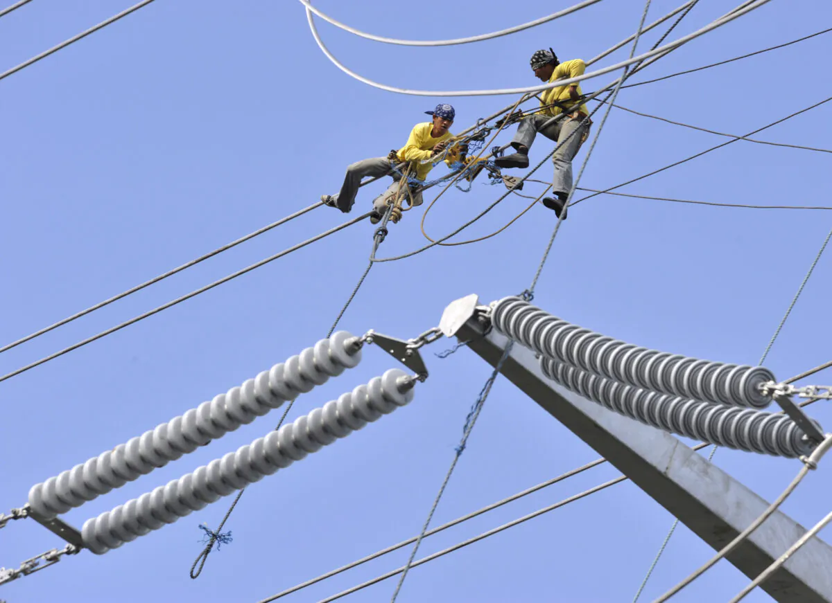 Linemen install cables on the Transco power transmission line in Santa Rosa town south of Manila as the Chinese-led consortium officially took over a 25-year concession of the Philippines' national electricity grid as part of the government's privatization program on Jan. 15, 2009. (Romeo Gacad/AFP via Getty Images)