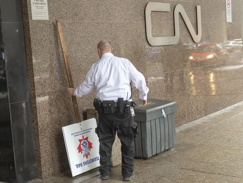 A security guard removes a picket sign in front of the CN headquarters as Canadian National Railway workers begin a nationwide strike on Nov. 19, 2019 in Montreal. The Teamsters union that went on strike this week claiming Quebec's propane shortage "appears to be largely manufactured" by Canadian National Railway Co. (The Canadian Press/Ryan Remiorz)