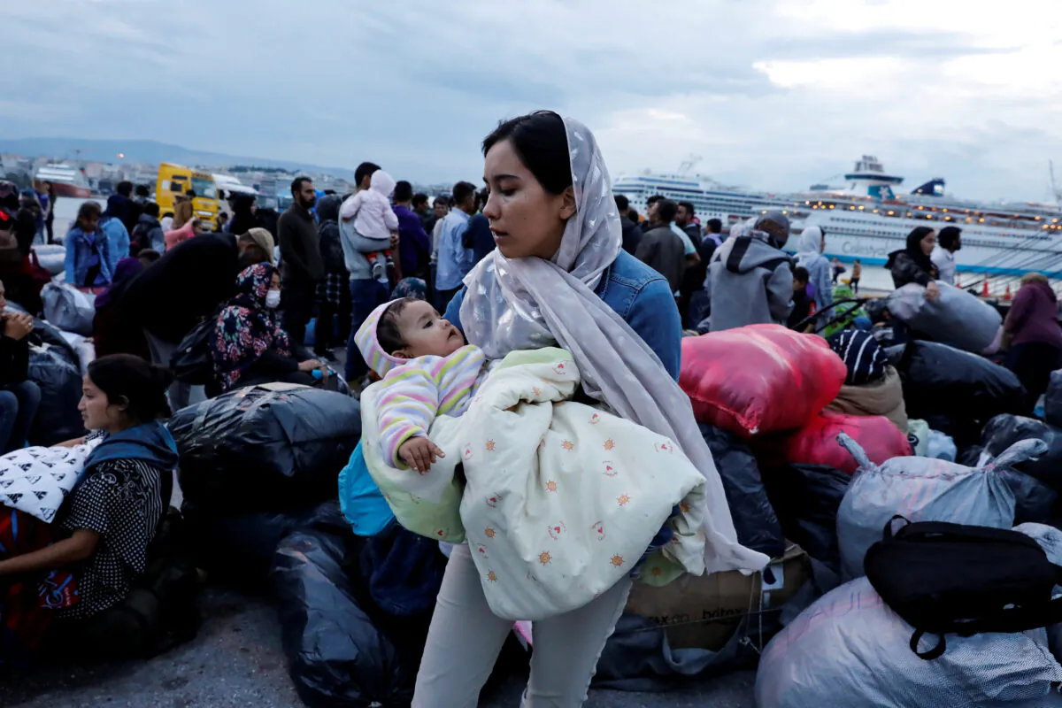 A woman holds her baby as refugees and migrants arrive on a passenger ferry from the island of Lesbos at the port of Piraeus, Greece, on Oct. 7, 2019. (Giorgos Moutafis/Reuters/File Photo)