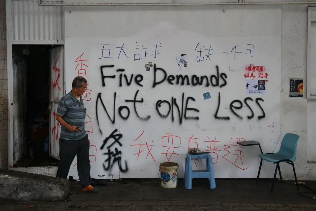 A man exits from a door in a wall covered in graffiti in Hong Kong on Oct. 7, 2019. (Nicolas Asfouri/AFP via Getty Images)