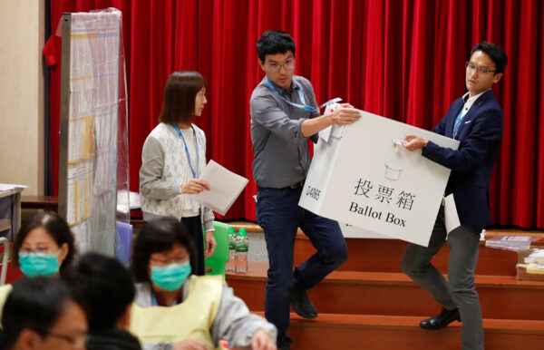 Polling officials carry a ballot box to count the votes of the Hong Kong council elections, in a polling station in Hong Kong