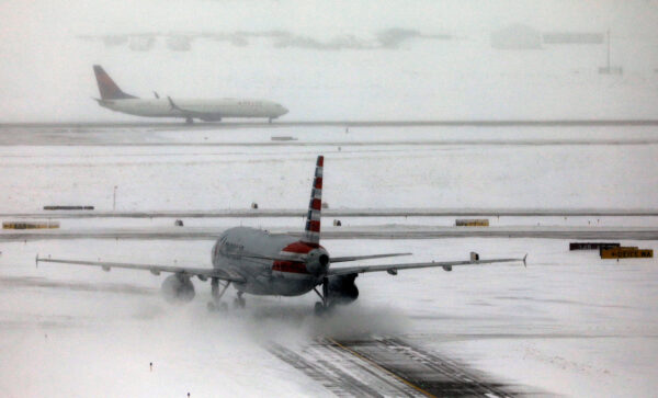 An American Airlines jet taxis down a snow-covered runway after a snowstorm at Denver International Airport