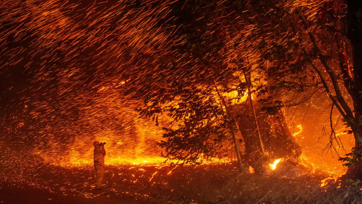 A photographer takes photos amidst a shower of embers as wind and flames rip through the area during the Kincade fire near Geyserville, Calif. on Oct. 24, 2019. (Josh Edelson/AFP via Getty Images)