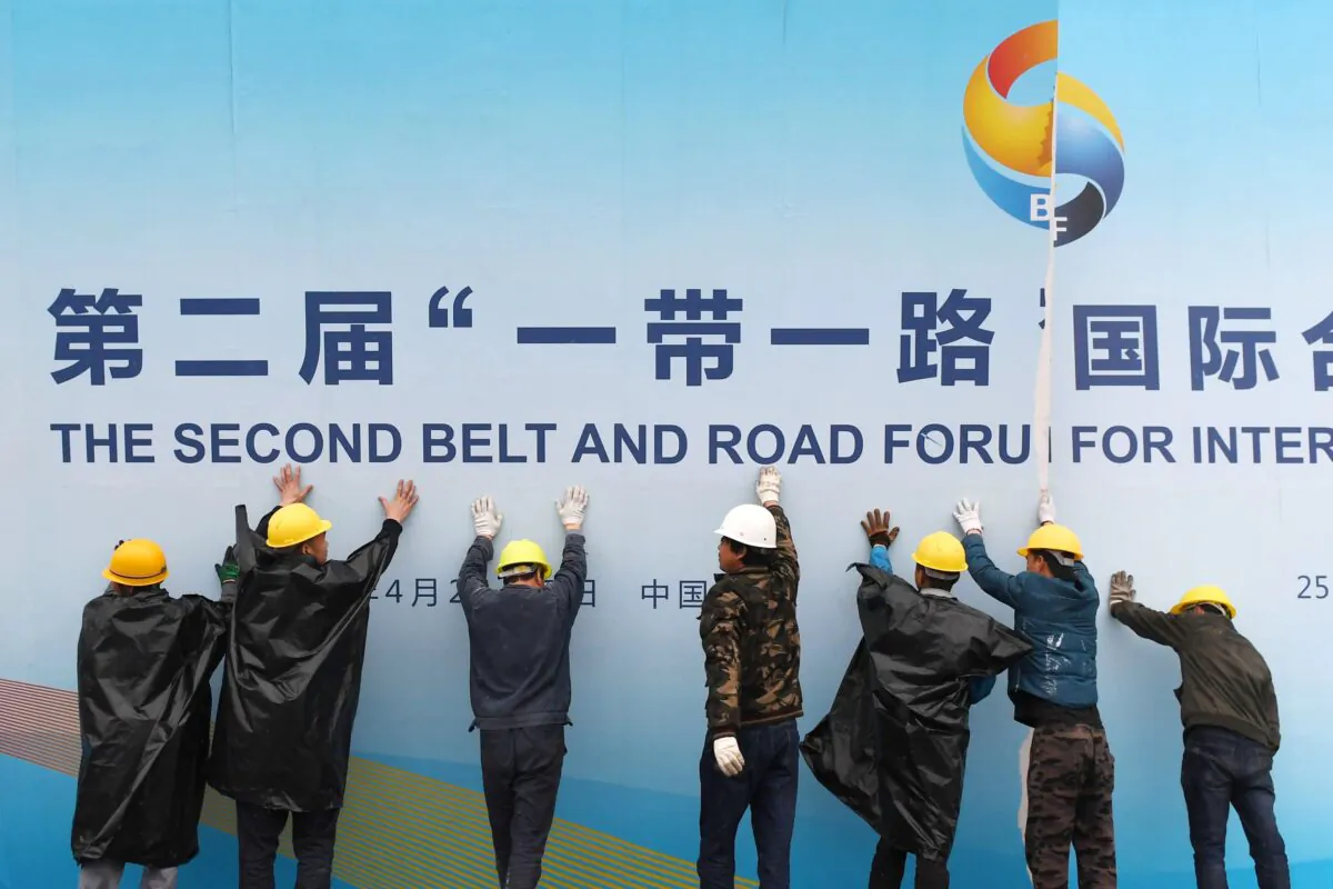 Workers take down a Belt and Road Forum panel outside the venue of the forum in Beijing on April 27, 2019. (Greg Baker/AFP via Getty Images)