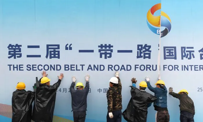 Workers take down a Belt and Road Forum panel outside the venue of the forum in Beijing on April 27, 2019. (Greg Baker/AFP via Getty Images)