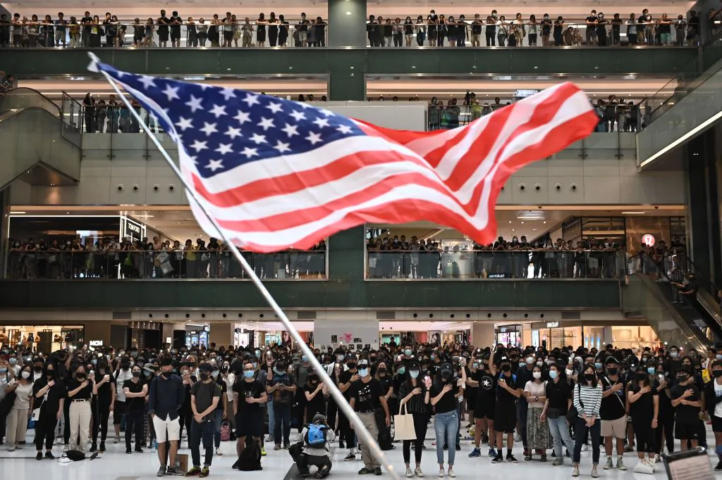 People wave the U.S. flag during a flash mob rally inside a shopping mall in Sha Tin district in Hong Kong on Oct. 13, 2019. (Philip Fong/AFP via Getty Images)