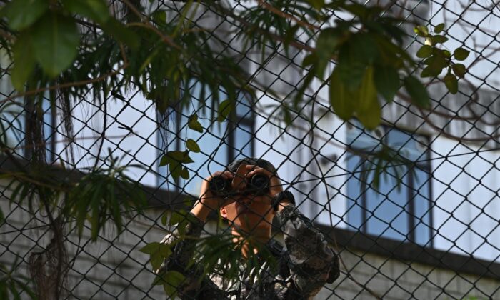 A Chinese People's Liberation Army (PLA) soldier uses binoculars by the perimeter fence of the PLA Hong Kong Garrison barracks on November 17, 2019. (PHILIP FONG/AFP via Getty Images)