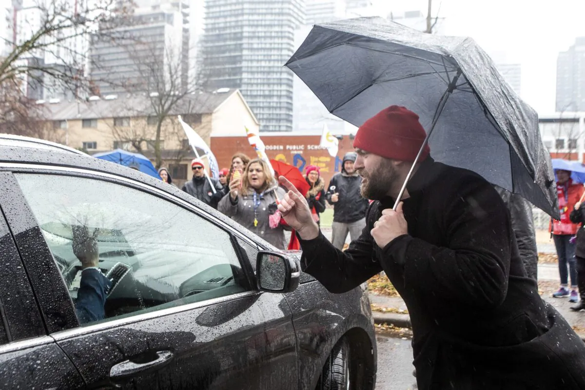 Protesting teachers gather around Ontario Education Minister Stephen Lecce's car as he leaves after making an announcement at a Toronto school on Nov. 27, 2019. Ontario public school teachers have embarked on job action as a result of a dispute with the provincial government. (The Canadian Press/Chris Young)