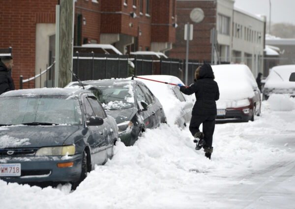 A woman clears snow from a car