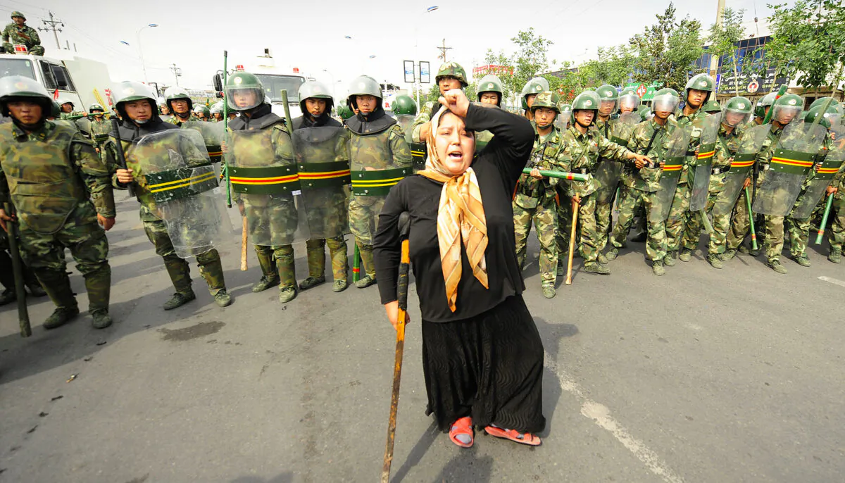 Chinese riot police watch a Muslim ethnic Uighur woman protest in Urumqi in China's far west Xinjiang province. (Getty Images | PETER PARKS)