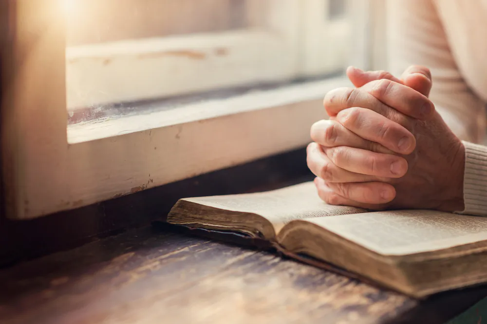 A person prays over a bible in a file photo. (Illustration/Shutterstock)