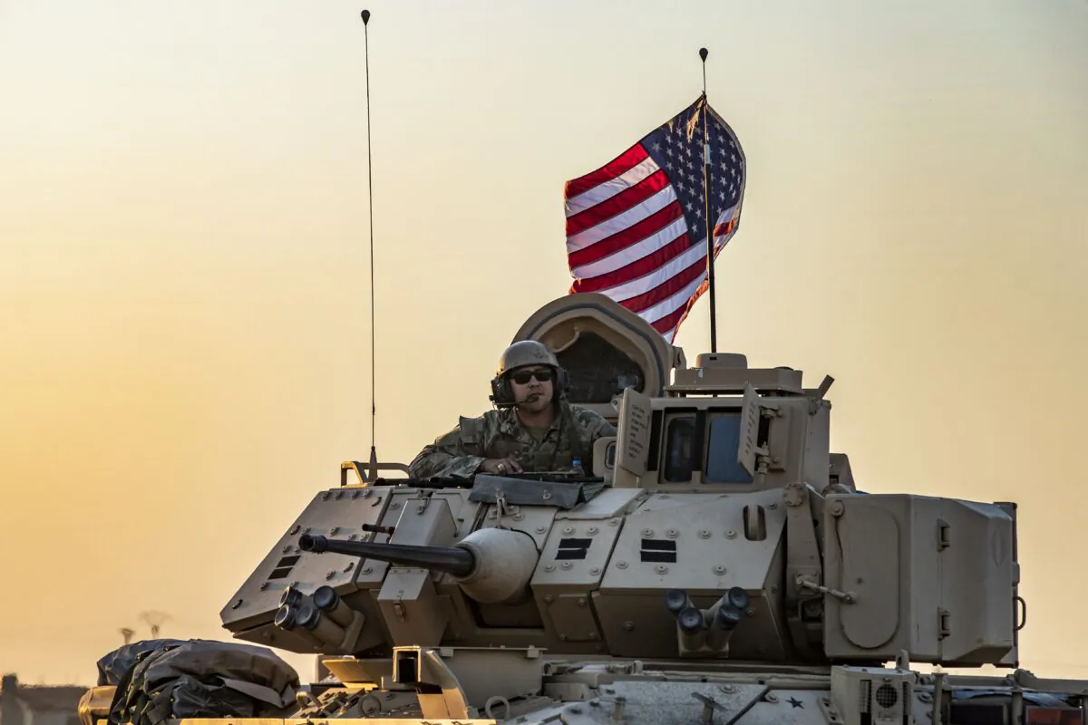 A U.S. soldier sits atop a Bradley armored personnel carrier as it drives near the town of Tal Tamr in the northeastern Syrian Hasakeh province on the border with Turkey, on Nov. 10, 2019. (Delil Souleiman/AFP via Getty Images)