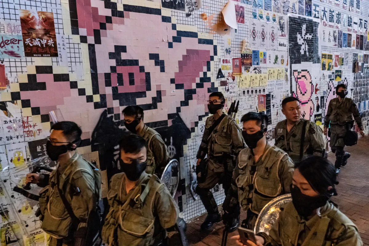 Riot police patrol in front of a so-called Lennon wall with the LIHKG Pig mascot ouside Tai Koo MTR station in Hong Kong, on Oct. 3, 2019. (Anthony Kwan/Getty Images)