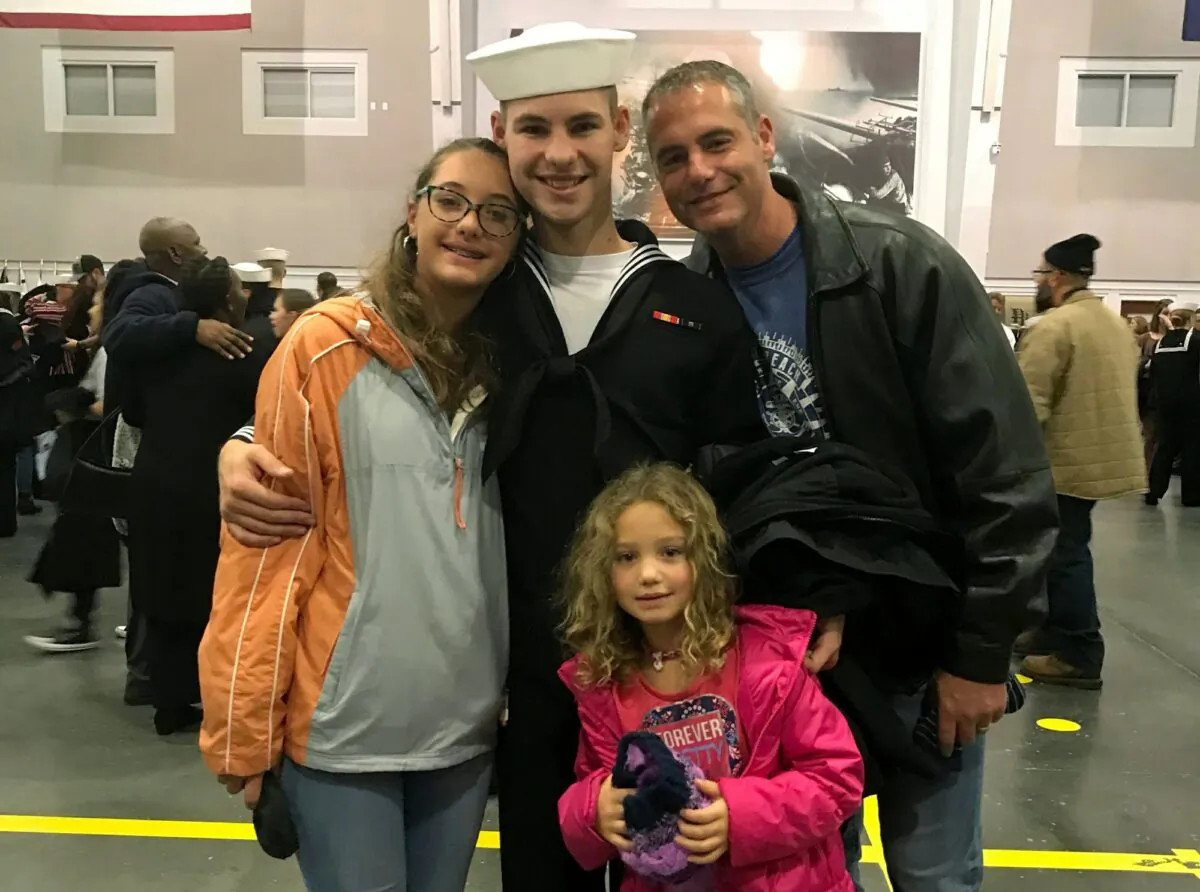 Cameron Walters (C) in Navy uniform, poses for a photo with his sisters and father, on Nov. 22, 2019, the day he graduated from boot camp in Great Lakes, Ill. (Heather Walters/Courtesy of the Walters Family via AP)
