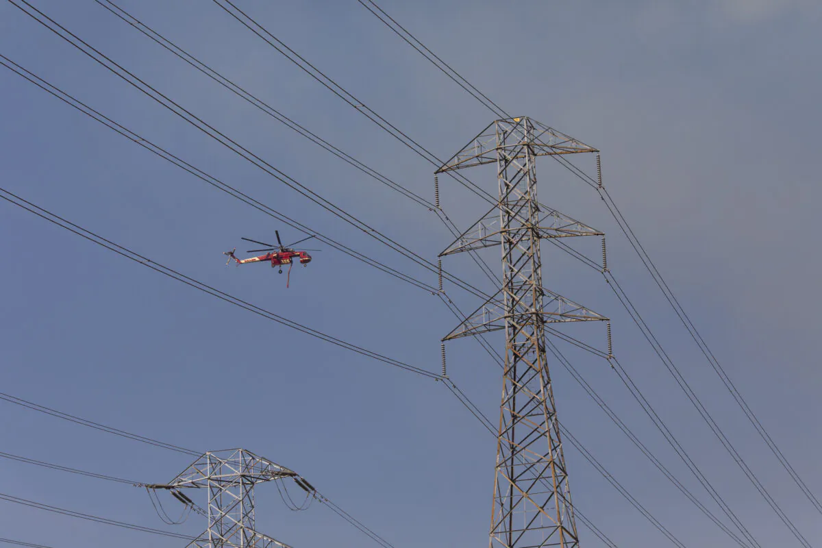 An air crane flies past PG&E power lines during firefighting operations in Healdsburg, Calif., on Oct. 26, 2019. (Philip Pacheco/AFP via Getty Images)