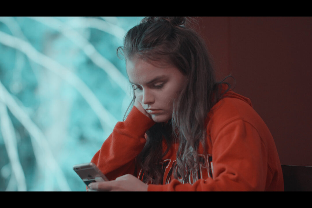Claire looking at her phone in "Like" (2019), a documentary film about social media. (IndieFlix)