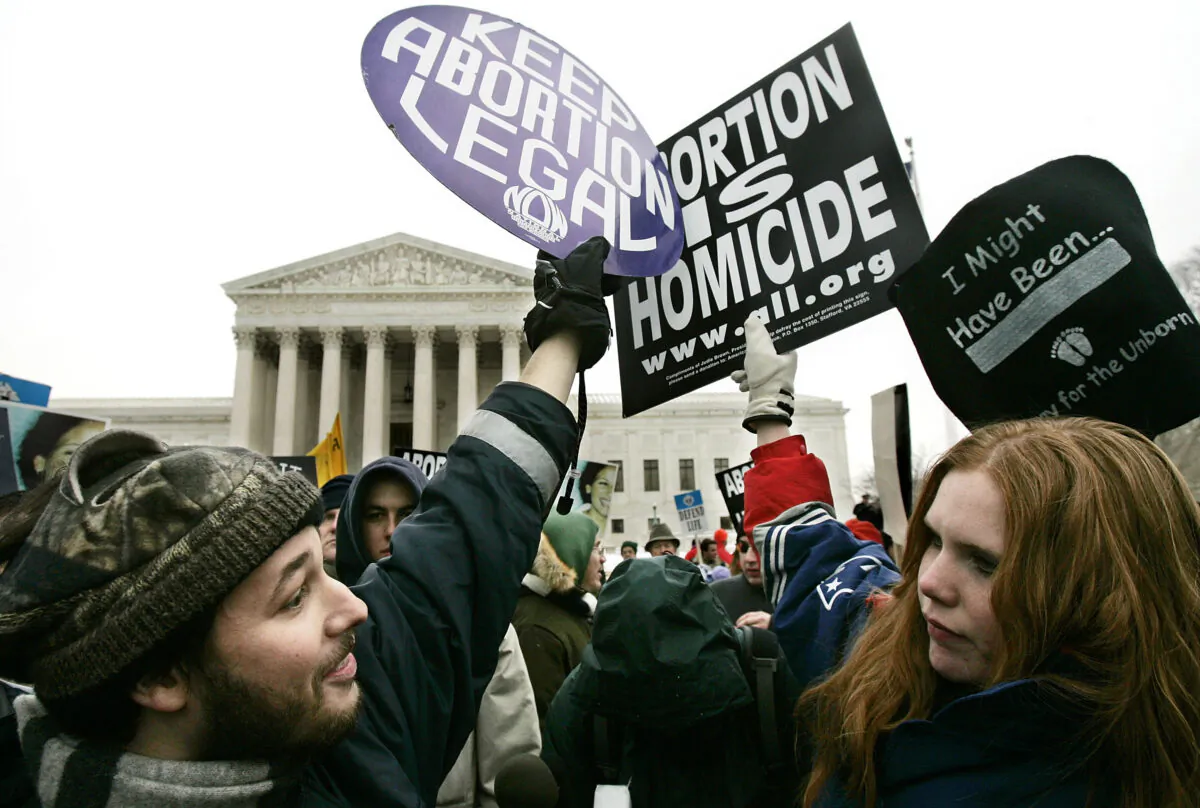 Pro-life activist Jessica Meunier (R) of Fitchburg, MA, and pro-abortion activist Luqman Clark (L) of Arlington, VA hold up signs as they protest outside U.S. Supreme Court during the "March for Life" event January 24, 2005 in Washington, DC. Alex Wong/Getty Images