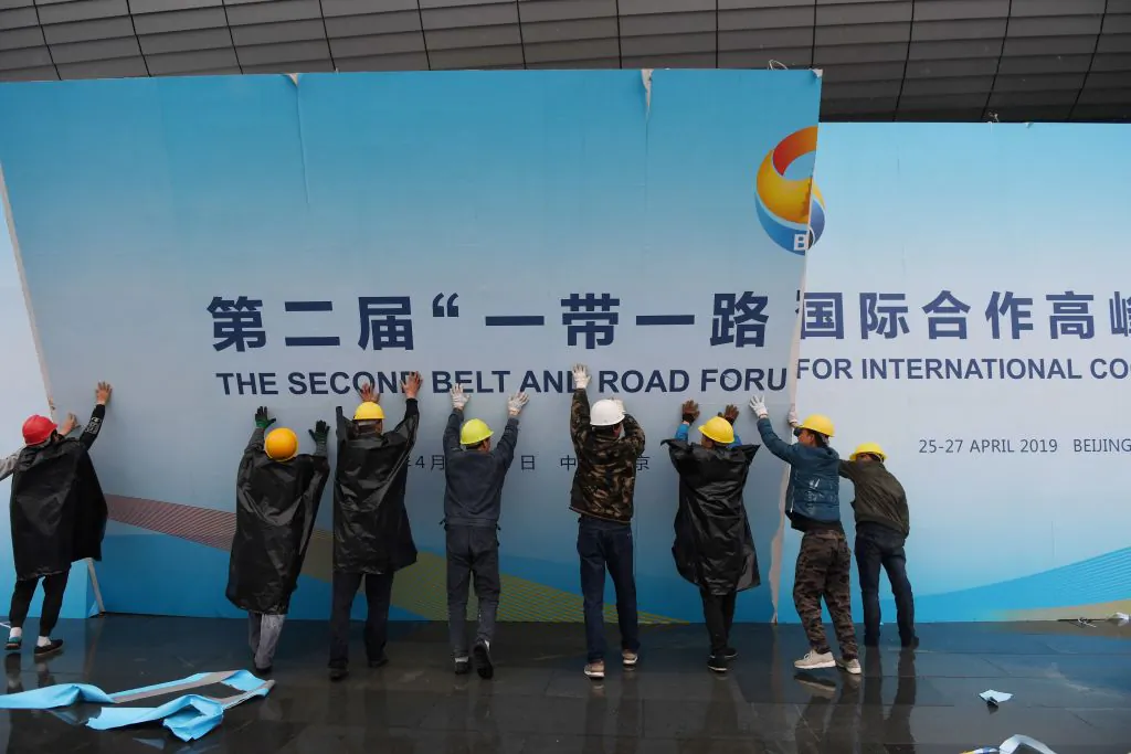 Workers take down a Belt and Road Forum panel outside the venue of the forum in Beijing on April 27, 2019. (Greg Baker/AFP via Getty Images)