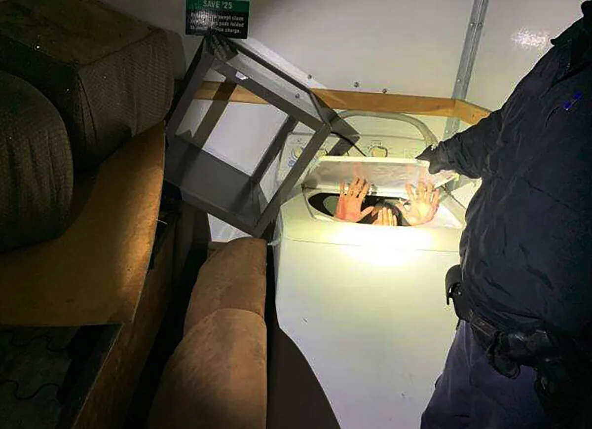 This photo released on Dec. 9, 2019 by U.S. Customs and Border Protection (CBP) shows hands held up by a person or persons hiding in a washing machine, among 11 Chinese nationals found by CBP agents hiding in furniture and appliances inside a moving truck stopped on Dec. 7 while entering the U.S. from Mexico at the San Ysidro border crossing near San Diego. (U.S. Customs and Border Protection via AP)