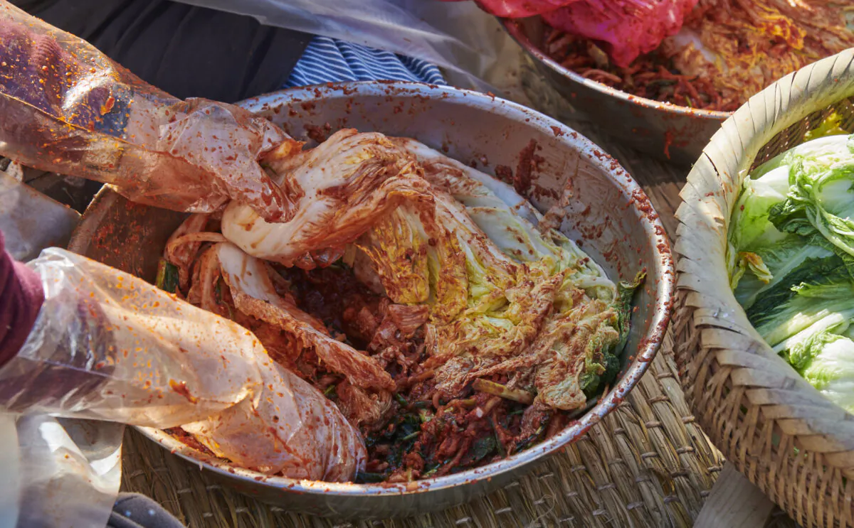 Coating heads of napa cabbage with a spicy, sour paste, to transform them into kimchi. (Courtesy of Nasoya)