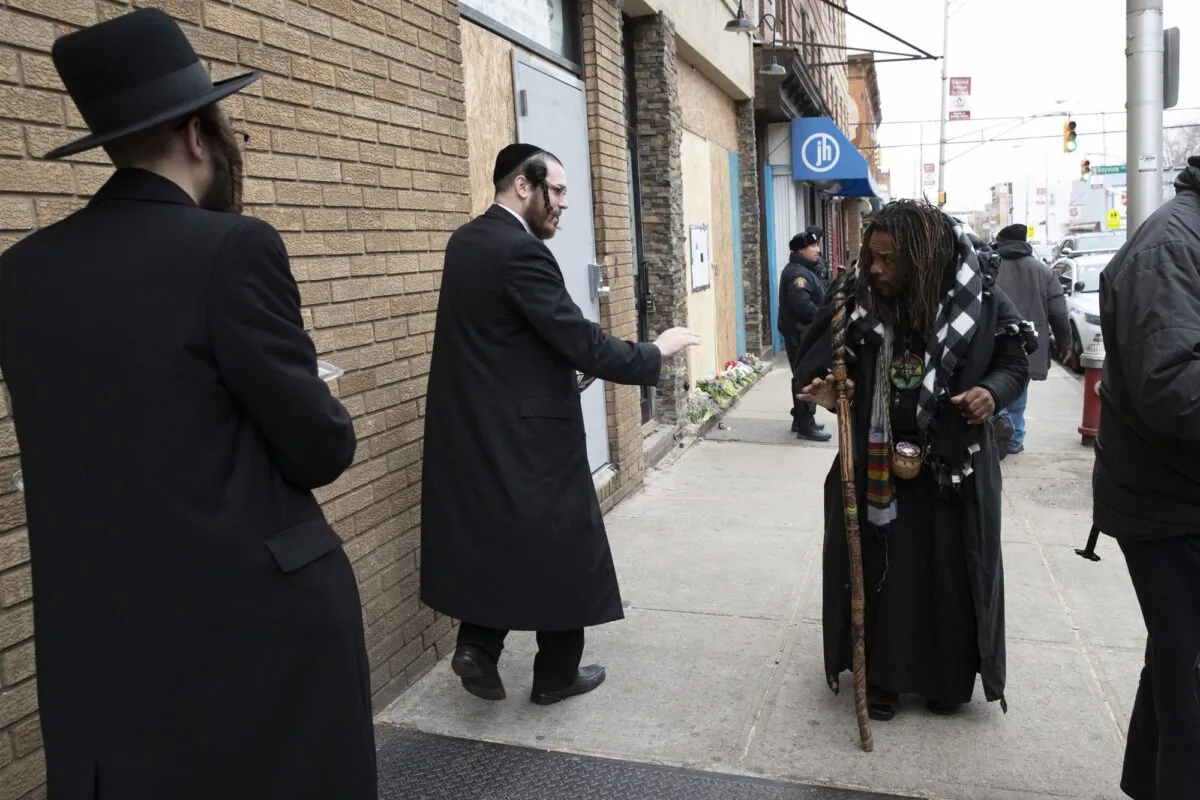 Robert McClain (R), offers condolences to two Jewish men, on Dec. 13, 2019 in Jersey City, N.J. close to the site where three people and two gunmen were shot. (AP Photo/Mark Lennihan)
