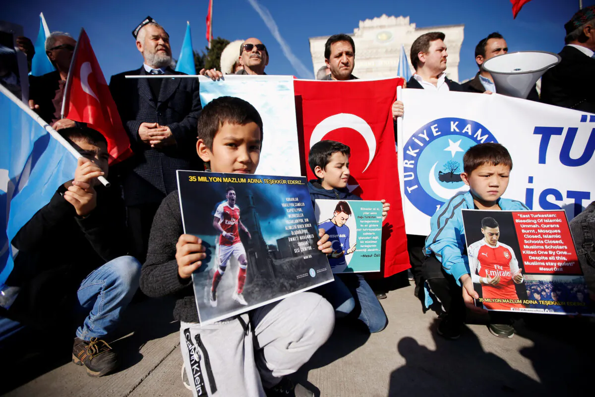 Ethnic Uyghur boys hold placards with pictures of English soccer club Arsenal's midfielder Mesut Ozil during a protest against China in Istanbul, Turkey on Dec. 14, 2019. The placard reads: "Thank you, Mesut Ozil, on behalf of 35 million oppressed."  (Kemal Aslan/Reuters)