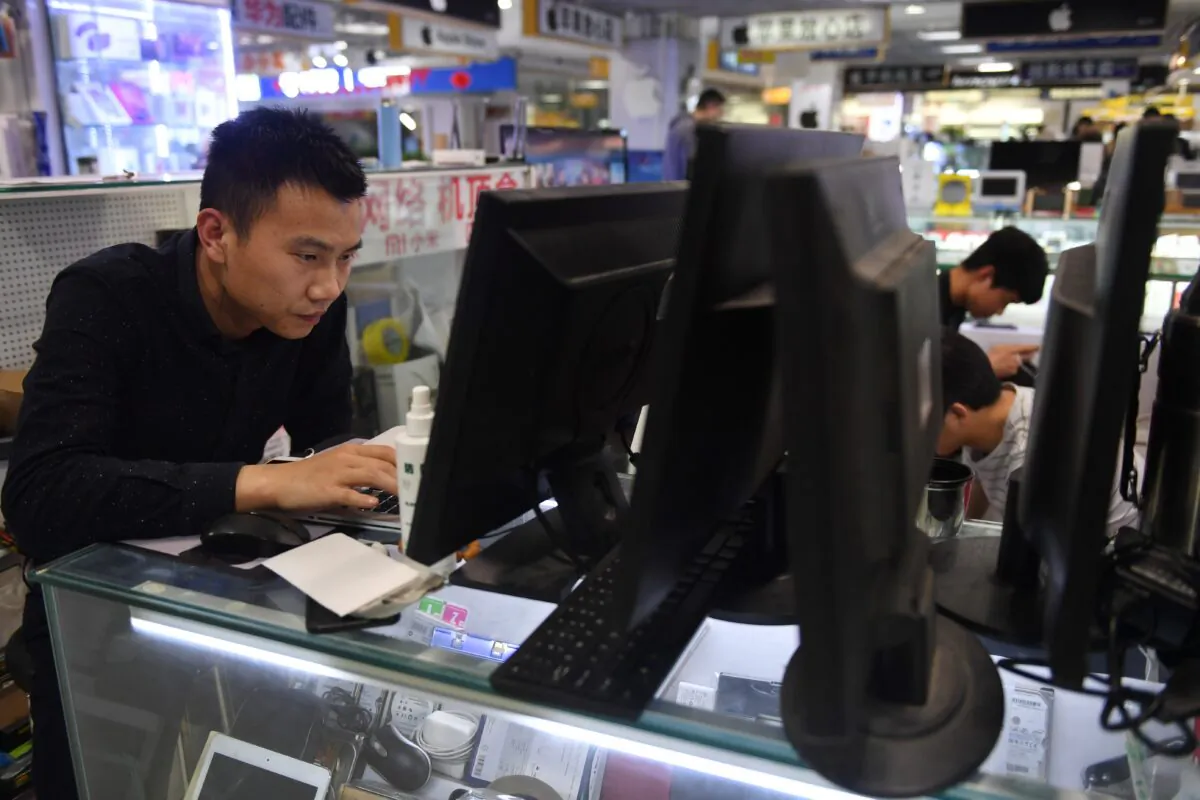 A man repairs a laptop in a computer mall in Beijing on March 30, 2018. (GREG BAKER/AFP via Getty Images)