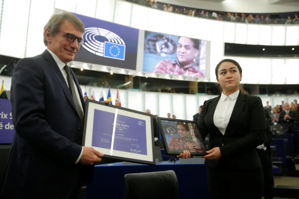 European Parliament President David-Maria Sassoli stands next to Jewher Ilham, daughter of Ilham Tohti, Uyghur economist and human rights activist, holding a portrait of her father during the award ceremony for his 2019 EU Sakharov Prize next to at the European Parliament in Strasbourg, France on Dec. 18, 2019.  (Vincent Kessler/Reuters)