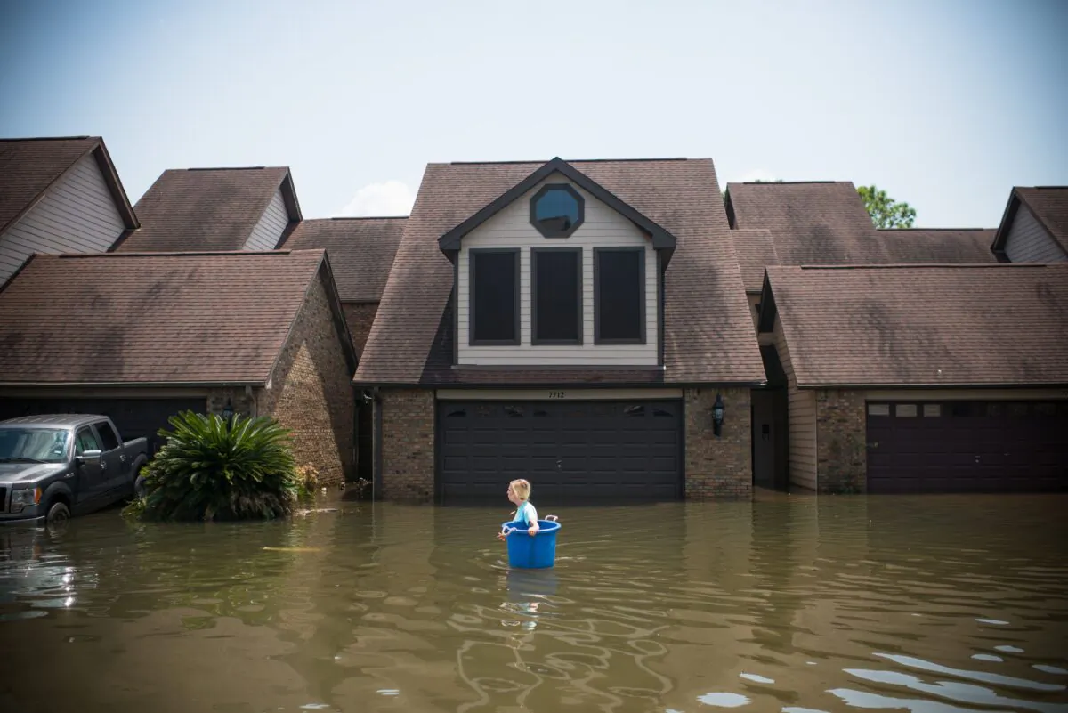 Jenna Fountain carries a bucket down Regency Drive to try to recover items from her flooded home after Hurricane Harvey, in Port Arthur, Texas, on Sept. 1, 2017.   (EMILY KASK/AFP via Getty Images)