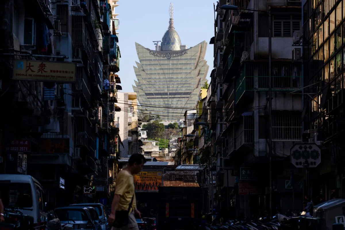 A pedestrian walks in a residential neighborhood in front of a view of the Grand Lisboa casino resort (back C) in Macau, on August 29, 2017. (Anthony Wallace/AFP via Getty Images)